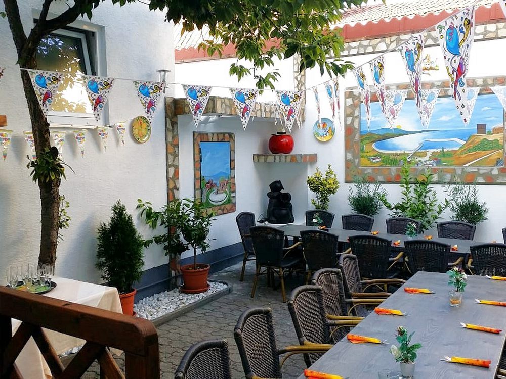 Biergarten im Innenhof mit langer Tafel, Wimpelketten und einem Wandbild vom Meer